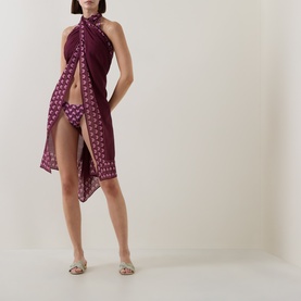 Model wearing Seafolly dark burgundy cotton sarong with geometric print border, styled with metallic flat sandals