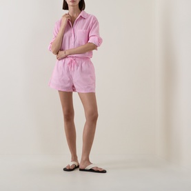 Model wearing Seafolly Light Pop Pink cotton shorts with matching shirt cover-up, styled with black flat sandals