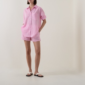 Model wearing Seafolly Light Pop Pink cotton shorts styled with matching shirt and black flat sandals
