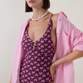 Model wearing Seafolly dark burgundy floral swimsuit, styled with a pink oversized shirt and pearl necklace.