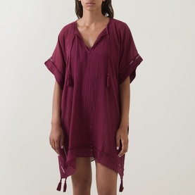 Model wearing Seafolly dark burgundy cotton cover-up with V-neck, tassel ties, short sleeves, and asymmetric hemline with tassel trim.