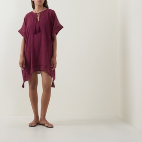 Model wearing Seafolly dark burgundy cotton cover-up with tassel tie neckline, short sleeves and high-low hem, styled with flat sandals.