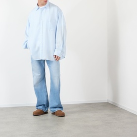 Model wearing Acne Stripe Logo Shirt in blue, oversized fit with classic collar, styled with light wash wide-leg jeans and tan suede loafers.
