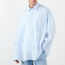 Model wearing Acne Stripe Logo Shirt in blue with white vertical stripes, oversized fit, classic collar, long sleeves, paired with light blue jeans.