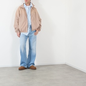 Model wearing Acne Stripe Logo Shirt in blue, styled with a beige zip jacket, light wash flared jeans and tan suede loafers.