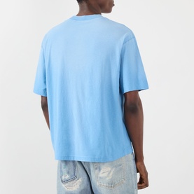 Model wearing Acne Sprayed Logo T-Shirt in cornflower blue, rear view, with dropped shoulders and straight hem, styled with light wash distressed