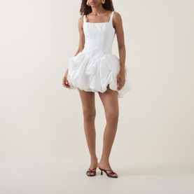 Model wearing Aje Alani Puff-Skirt Mini Dress in ivory, featuring corset-style bodice, square neckline, and voluminous puff skirt, styled with brown