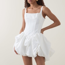 Model wearing Aje Alani Puff-Skirt Mini Dress in ivory, featuring corset-style bodice, square neckline, and voluminous puff skirt