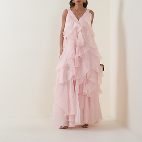 Model wearing Aje Athena Ruffle Gown in Tea Blossom, sleeveless maxi dress with V-neckline and tiered ruffles, styled with strappy sandals