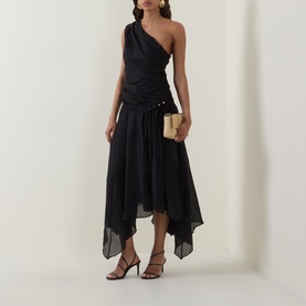 Model wearing black one-shoulder ruched asymmetric midi dress, styled with gold drop earrings, nude strappy heels, and a woven clutch bag