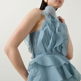 Model wearing Aje Cleo Ruffle Gown in duck egg, showing ruffle detailing, smocked sides, and pleated bodice on sleeveless silhouette.