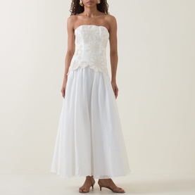 Model wearing Aje Gia Embroidered Off-The-Shoulder Gown in ivory, featuring floral embroidered bodice and full midi skirt, styled with nude heeled