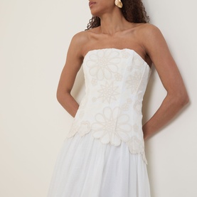 Model wearing Aje Gia Embroidered Off-The-Shoulder Gown in ivory, featuring floral embroidered strapless bodice and full skirt, styled with gold