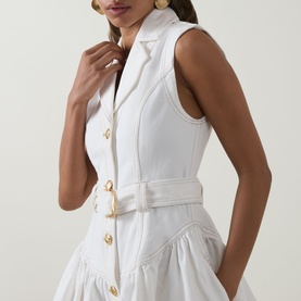 Model wearing Aje Liliana Denim Mini Dress in ivory, showing notched lapels, gold buttons, and sculptural belted waist detail.