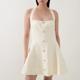 Model wearing Aje Monroe Halter Mini Dress in Butter, featuring halter neck, gold metal buttons, A-line silhouette and mini length