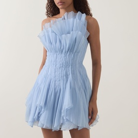 Model wearing Aje Nisha Off-The-Shoulder Mini Dress in Cloud Blue with ruffle trim, shirred waist, and flared mini skirt