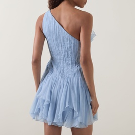 Model wearing Aje Nisha Off-The-Shoulder Mini Dress in Cloud Blue with shirred waist, ruffled hem, rear view