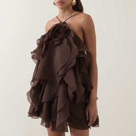 Model wearing Aje Pandorea Ruffle Mini Dress in Carob, halter neck with 3D rosette detail, layered ruffles, mini length voluminous silhouette