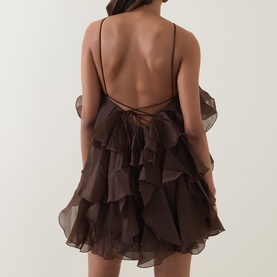 Model wearing Aje Pandorea Ruffle Mini Dress in Carob, showing open back with tie fastening and layered organza ruffles