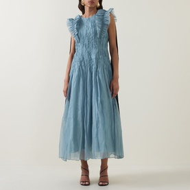 Model wearing Aje Mathilde Dress in Duck Egg, featuring ruffle shoulders, pintuck detail, and flared midi skirt, styled with strappy heeled sandals.