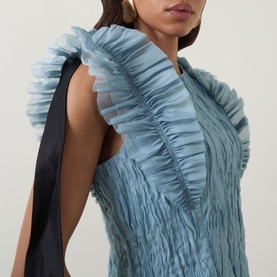 Model wearing Aje Mathilde Dress in Duck Egg with ruched tulle frill shoulders, contrast black tie detail and pintuck texture throughout.