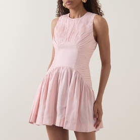 Model wearing Aje Medea Pleated Mini Dress in Tea Blossom, sleeveless with pleated bodice and ruffled flared mini skirt.