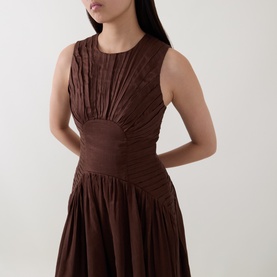 Model wearing Aje Dark Chocolate linen-viscose dress with ruched bodice, cinched waist and pleated skirt, sleeveless style
