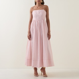 Model wearing Aje Rosie Dress in Tea Blossom; straight neckline, shoulder straps, gathered midi skirt. Styled with nude heeled sandals.