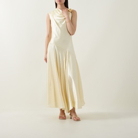 Model wearing Aje Siren Ruffled Dress in Butter, sleeveless midi with asymmetric hem and cowl neckline, styled with tan strappy heels