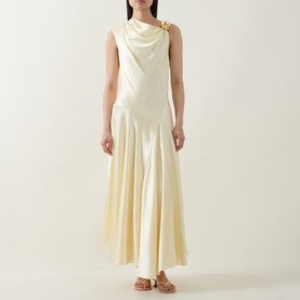 Model wearing Aje Siren Ruffled Dress in butter, sleeveless satin midi with cowl neck, gold-toned hardware detail, asymmetric hem; styled with tan