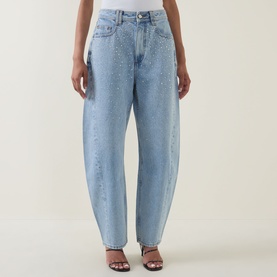 Model wearing Aje Lucina High-Rise Stud Barrel Jeans in light wash blue with stud embellishment, styled with black heeled sandals.