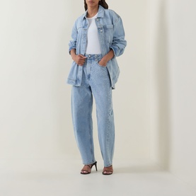 Model wearing Aje Lucina High-Rise Stud Barrel Jeans in light wash blue with matching denim jacket, white tee and heeled sandals.