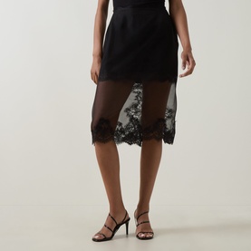 Model wearing Aje Ophelia Lace-Trim Skirt in black, sheer midi length with floral lace hem, styled with black strappy heels