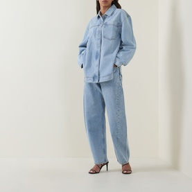 Model wearing Aje Lucina Denim Shirt in Light Wash Blue with matching wide-leg denim jeans and strappy heeled sandals.