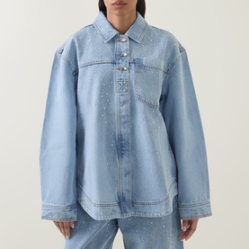 Model wearing Aje Lucina Denim Shirt in light wash blue with raised stud detail, dropped shoulders, and snap-cuff long sleeves, styled with matching