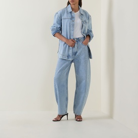 Model wearing Aje Lucina Denim Shirt in Light Wash Blue with matching wide-leg denim jeans and black heeled sandals.