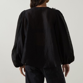 Model wearing Aje Demi Blouse in black, showing rear view with blouson sleeves, elasticated cuffs and subtle sheen finish.