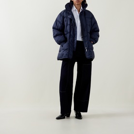 Model wearing HIGH dark blue quilted puffer coat, styled with wide-leg black trousers and a white shirt