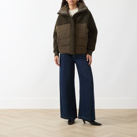 Model wearing HIGH olive puffer coat with contrast panelling, styled with wide-leg dark denim jeans and black heels