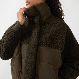 Model wearing HIGH olive coat with teddy fleece and quilted panels, high funnel neck, close-up detail shot