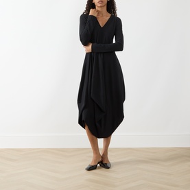 Model wearing HIGH black long-sleeve V-neck midi dress with draped asymmetric hem, styled with black flat shoes.