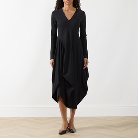 Model wearing HIGH black long-sleeve V-neck midi dress with draped cocoon hem, styled with dark flat shoes.