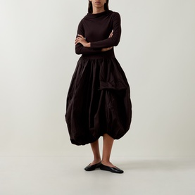 Model wearing HIGH brown dress with voluminous gathered skirt and fitted long-sleeve top, styled with black flat shoes