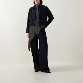 Model wearing HIGH navy jacket with asymmetric hem, styled with wide-leg dark trousers and brown shirt