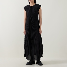 Model wearing HIGH black sleeveless maxi dress with gathered front detail and asymmetric pleated skirt, styled with black loafers