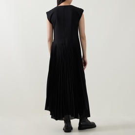 Model wearing HIGH black sleeveless midi dress with pleated skirt, styled with black chunky loafers, rear view