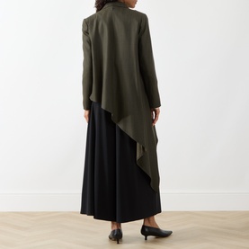 Model wearing HIGH khaki wool-lyocell asymmetric jacket, styled with black wide-leg trousers and black heels, rear view.