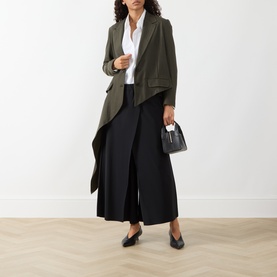 Model wearing HIGH khaki wool-lyocell jacket with draped lapels, styled with white shirt, black wide-leg trousers and black loafers