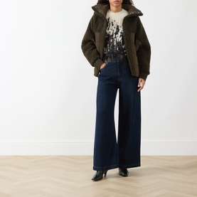Model wearing HIGH multi knitwear top styled with dark olive puffer jacket, wide-leg dark indigo jeans and black heeled boots