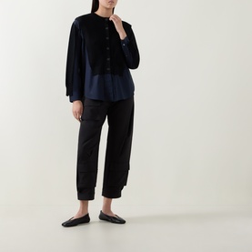 Model wearing HIGH black wool shirt with button front, styled with black tapered trousers and flat mules